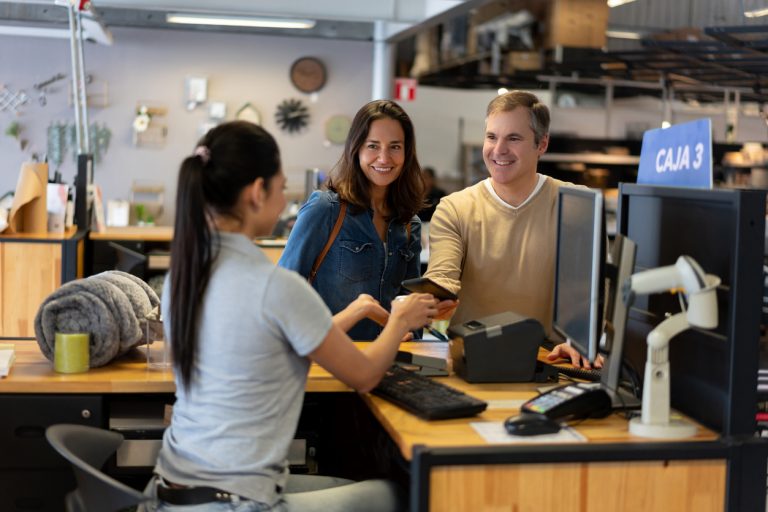 Adult couple at a furniture store paying at the cashier with a smartphone contactless payment