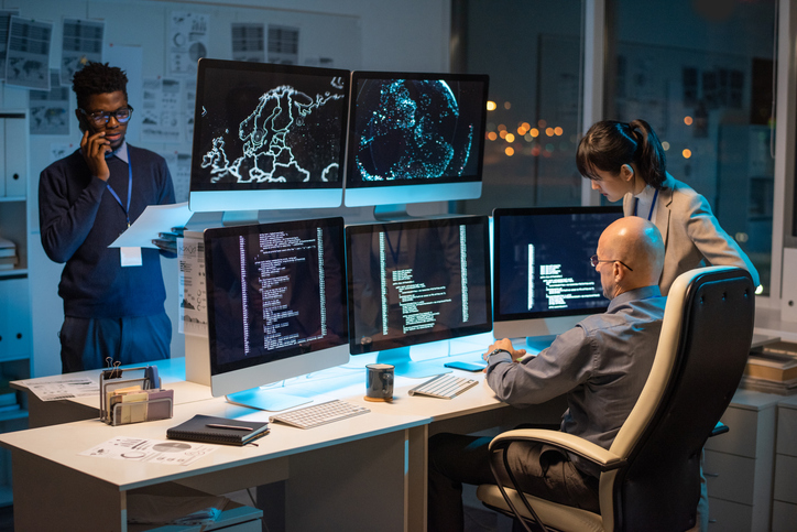 Cisco WebEx – Two colleagues sitting in front of computer monitors troubleshooting
